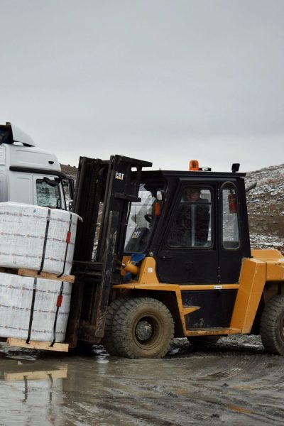 Forklift transporting large pallet in an outdoor industrial setting.