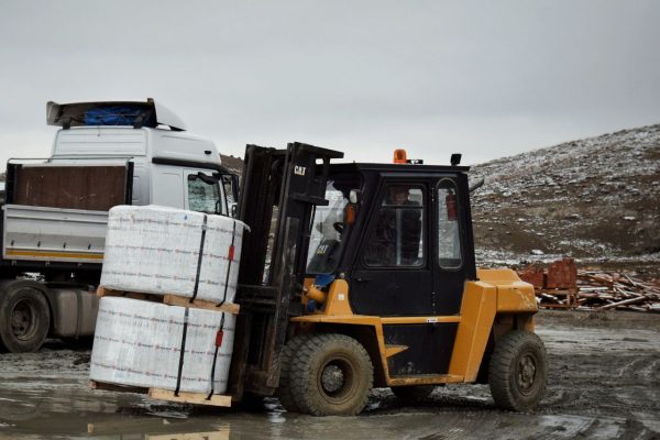 Forklift transporting large pallet in an outdoor industrial setting.